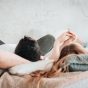 Young,Straight,Couple,Laying,On,Backs,On,Bed,Holding,Hands.