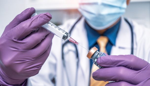 Close,Up,Doctor's,Hand,In,Purple,Gloves,Holding,Medicine,Bottle