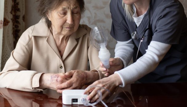 Young,Female,Doctor,Holding,Oxygen,Mask,Over,Senior,Woman,Patient's