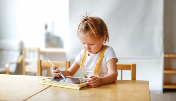 Funny cute baby girl toddler with tablet, child and gadget. Early development and drawing on the screen, the child plays and learns on the tablet