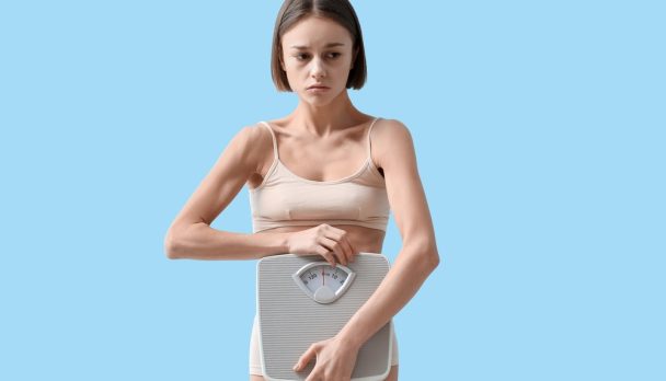 Young,Woman,With,Weight,Scales,On,Color,Background.,Anorexia,Concept