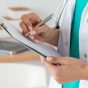 Close-up,View,Of,Female,Doctor,Hands,Filling,Patient,Registration,Form.