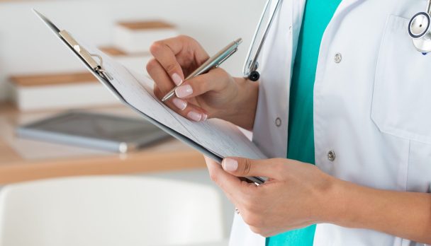 Close-up,View,Of,Female,Doctor,Hands,Filling,Patient,Registration,Form.